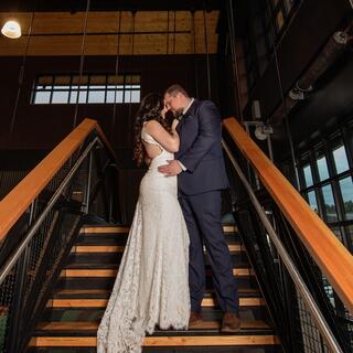 A couple shares a romantic kiss on a staircase, dressed in elegant wedding attire, capturing a moment of love and intimacy.