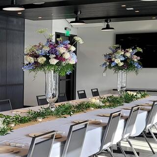 A beautifully set dining table features lush floral arrangements and greenery, creating an elegant atmosphere for a special event.
