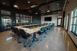 A modern conference room featuring a long table, ergonomic chairs, large windows, and a sleek design suitable for meetings.