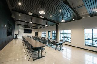 A spacious conference room features a long table flanked by chairs, modern lighting, and large windows, creating a bright, inviting atmosphere.
